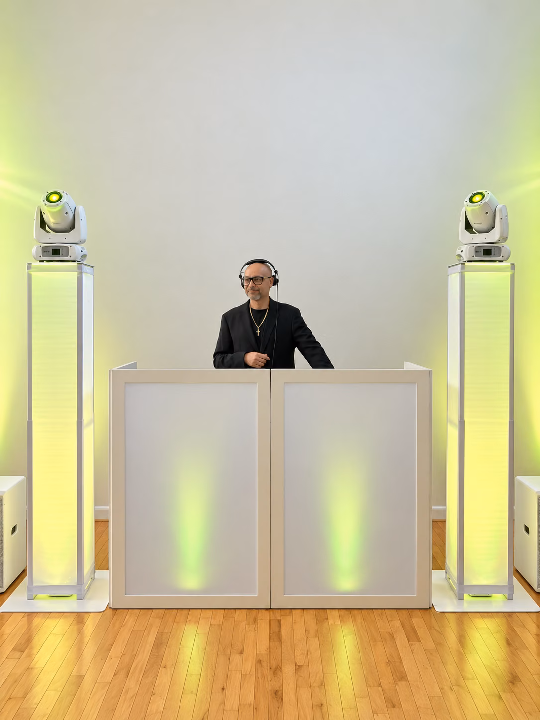 DJ EV in headphones behind the booth in warm green light