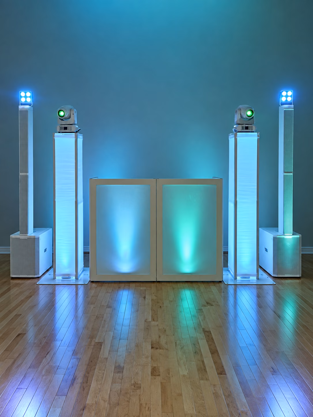 White DJ booth between column speakers and moving-head lights in teal